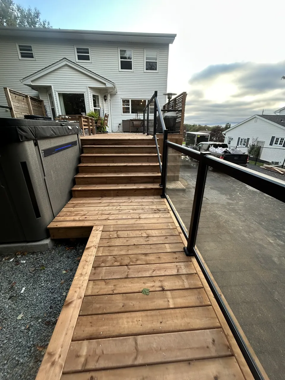 Terraced deck & glass rails: wood walkway and stairs beside the house